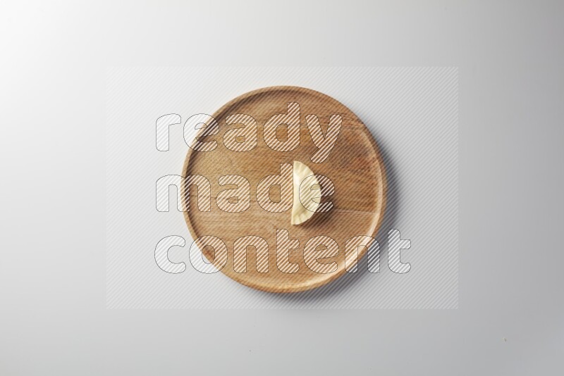 A single Sambosa on a wooden round plate on a white background