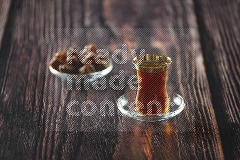A tea glass cup with dates and coffee on wooden background