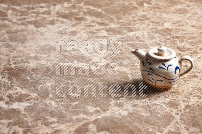 A pottery teapot on beige marble background