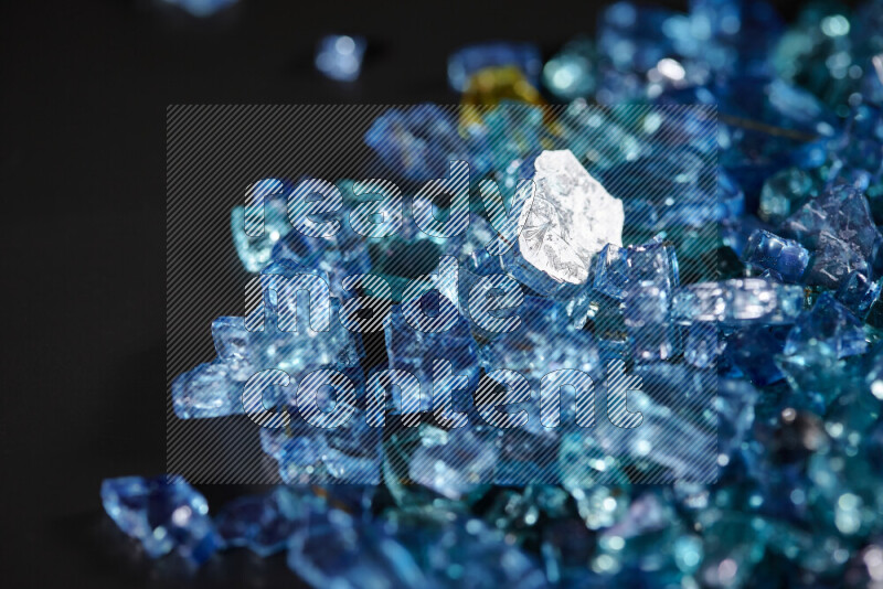 Transparent blue fragments of glass scattered on a black background