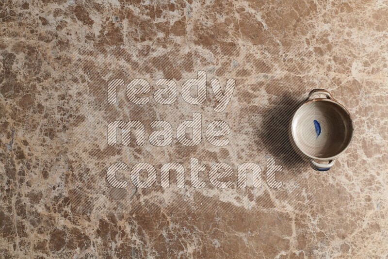 A multicolored pottery bowl on beige marble background