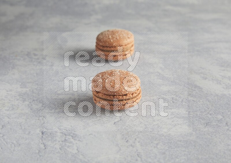 45º Shot of two Brown Hazelnuts macarons  on white  marble background