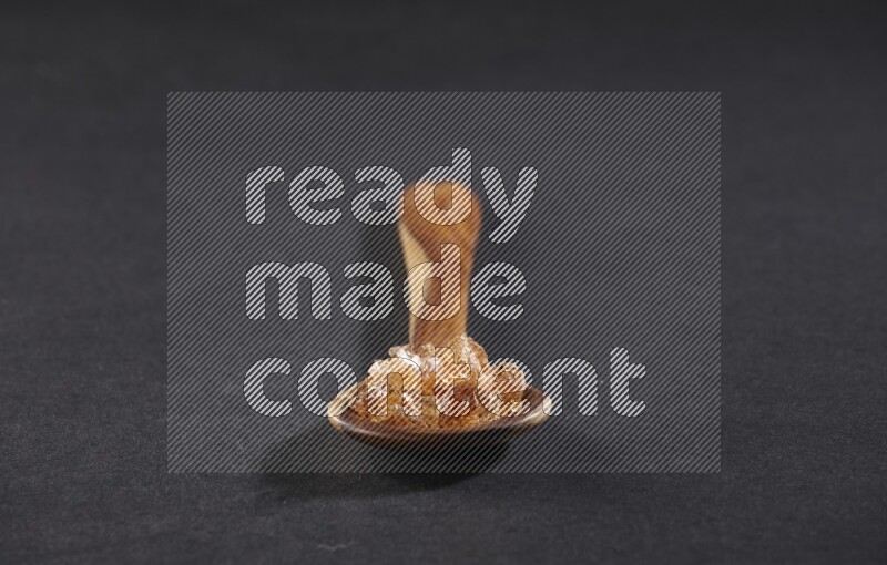 ملعقة خشبية كبيرة ممتلئة بقطع الصمغ العربي علي خلفية سوداء