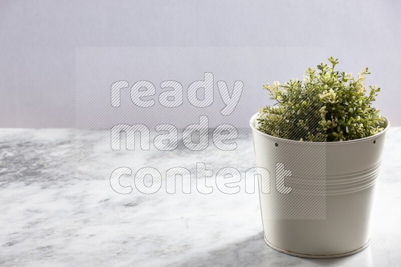 Artificial plant in white pot on grey marble background