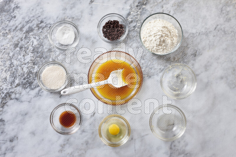 Cookies step by step with its ingredient, flour, butter, brown sugar, egg, vanilla extract, white sugar, chocolate chips and baking soda on grey marble background