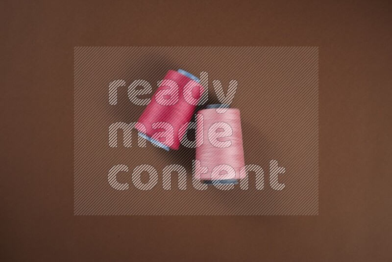 A pink collection of sewing and tailoring tools arranged on a brown background