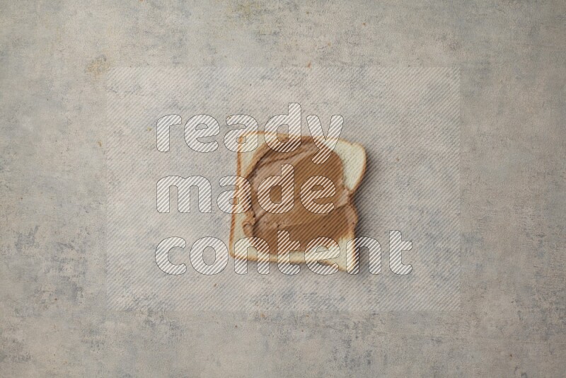 Creamy peanut butter on a white toast on a light blue textured background