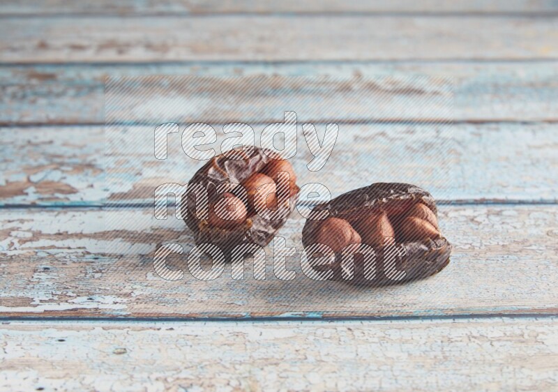 two hazelnuts stuffed madjoul dates on a light blue wooden background