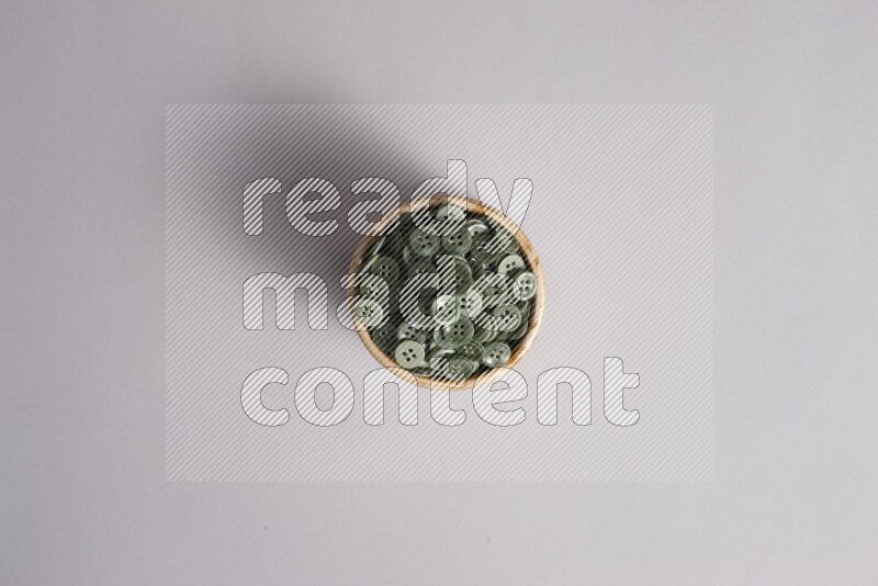 Colored buttons in a beige pottery bowl on grey background