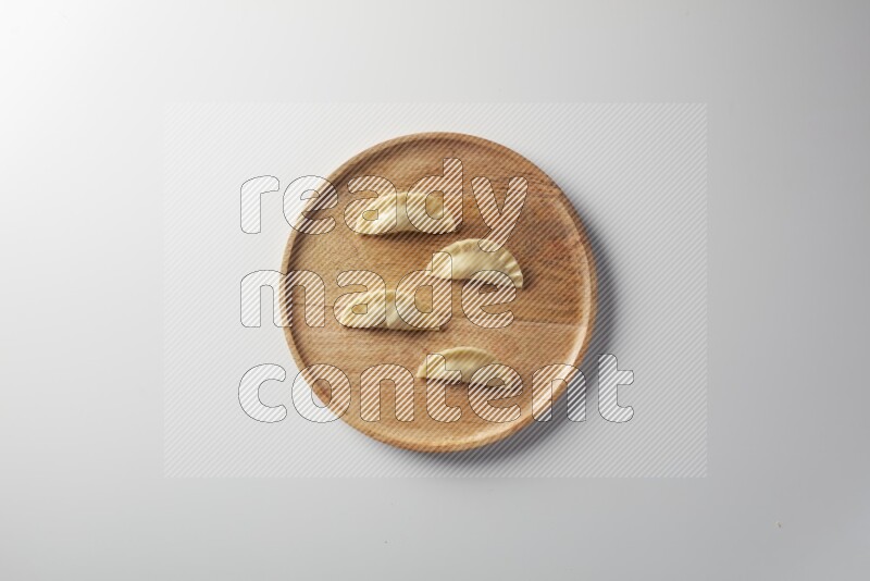 Four Sambosas on a wooden round plate on a white background