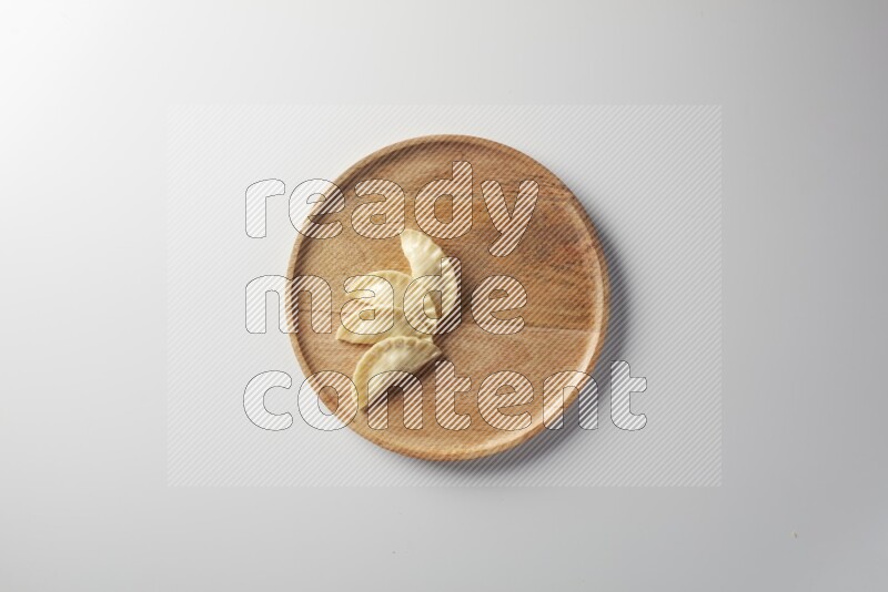 Four Sambosas on a wooden round plate on a white background