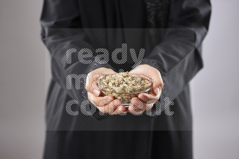 Woman in abaya holding different kinds of spices in different positions