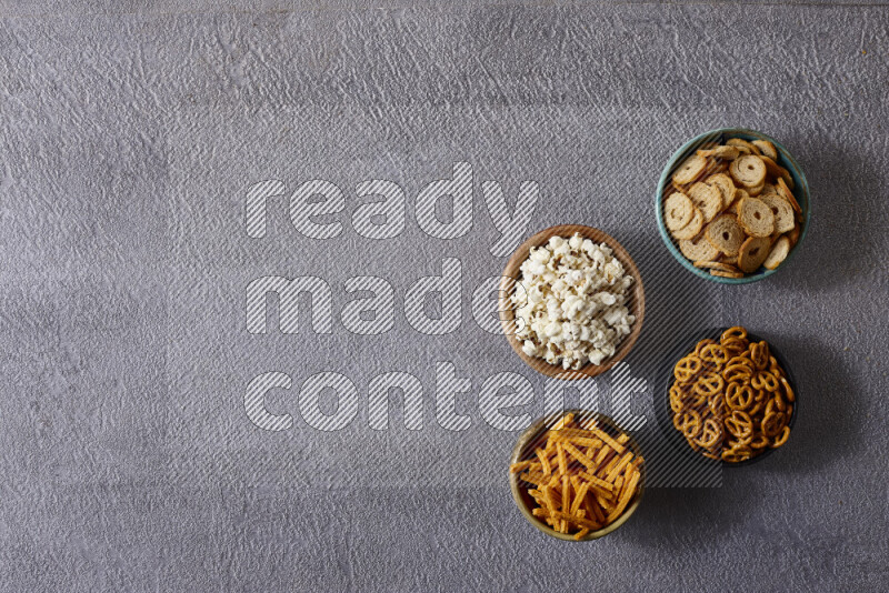 Assorted snacks in pottery bowls on grey background