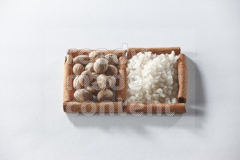 2 squares of cinnamon sticks full of white salt and nutmegs on white flooring