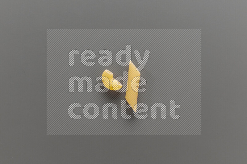 Elbow pasta with other types of pasta on grey background