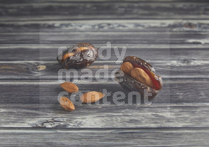 two almond stuffed madjoul dates on a wooden grey background