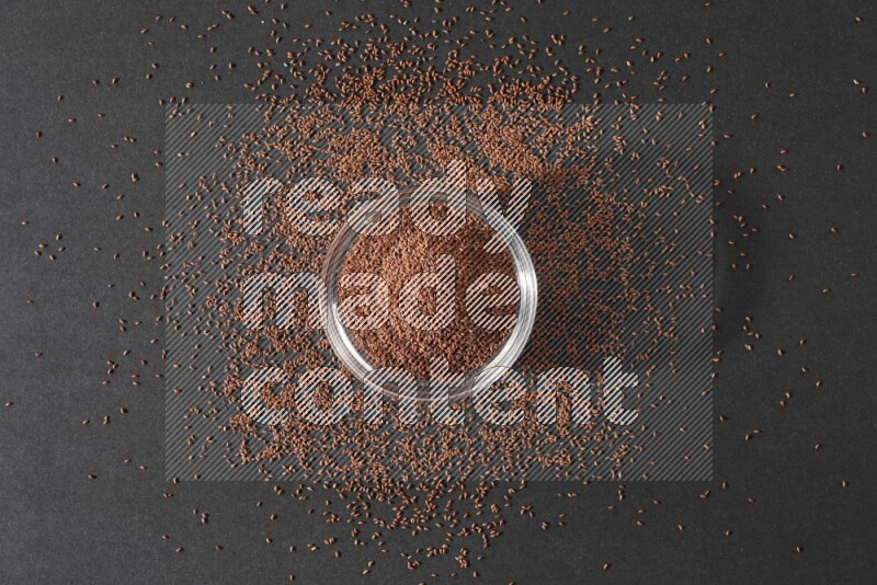 وعاء زجاجي ممتلئ ببذور حب الرشاد محاط بالبذور على أرضية سوداء