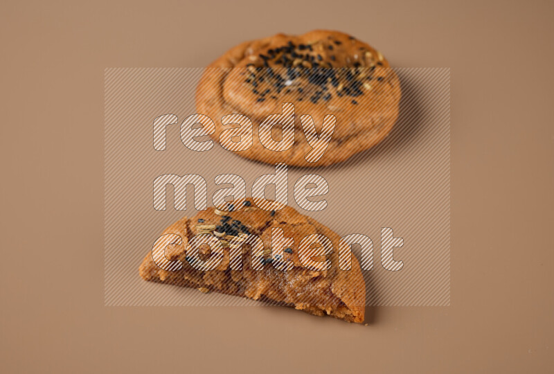 a Hasawi cookie field of date and herbs with another one cut in half on a brown background