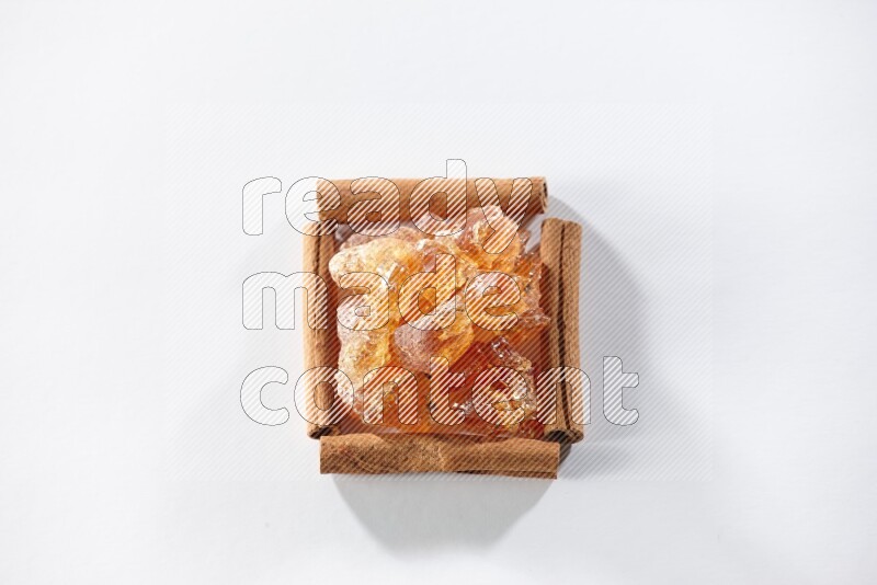 A single square of cinnamon sticks full of Arabic gum on white flooring