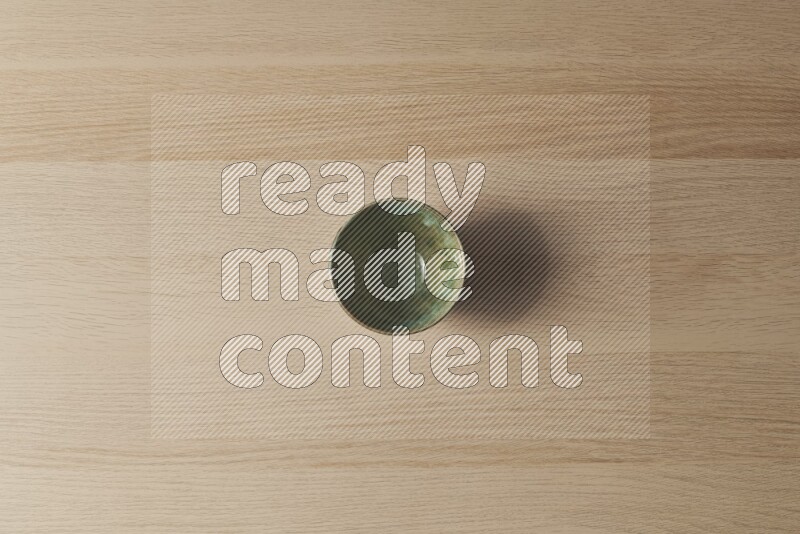A dark green pottery bowl on light wooden background