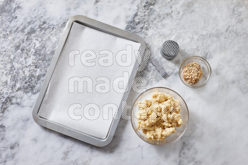 كحك خطوة بخطوة بمكوناته سمن، سكر، دقيق، سمسم، خميرة، ماء ونكهة الكحك على خلفية رخام رمادي