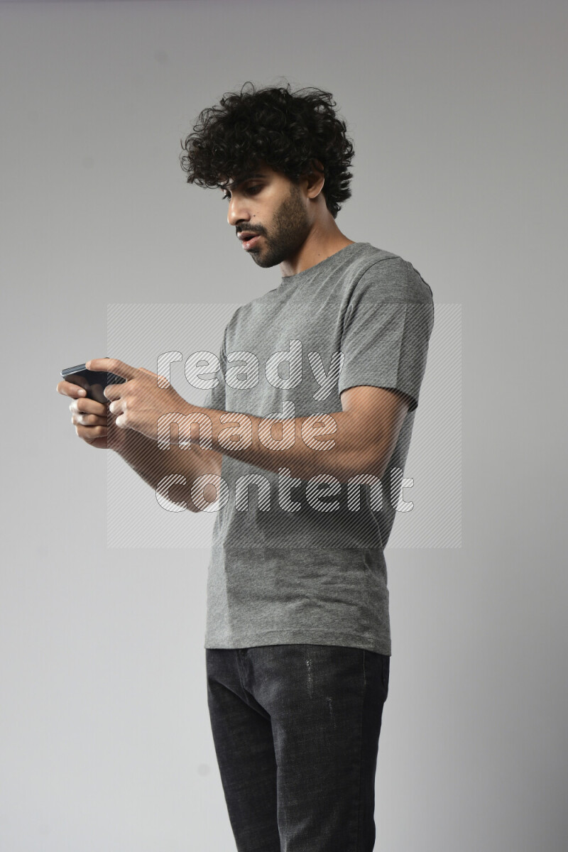 A man wearing casual standing and gaming on the phone on white background