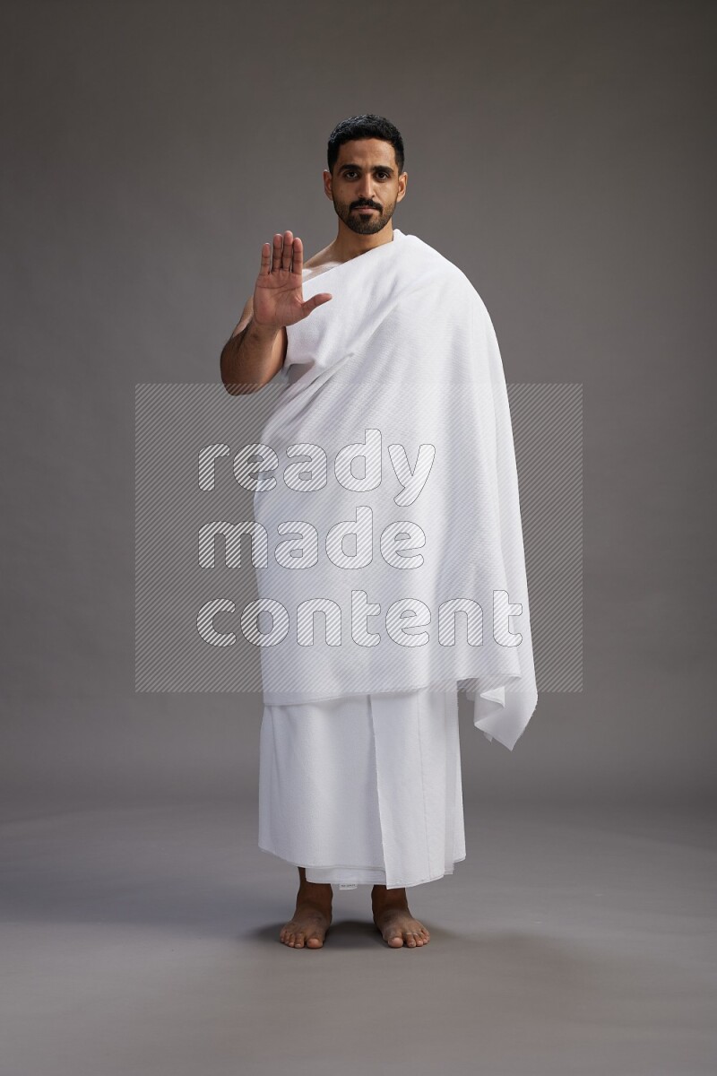 A man wearing Ehram Standing Interacting with the camera on gray background