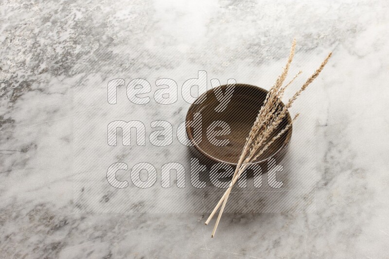 Wheat stalks on multicolored pottery oven plate on grey marble background