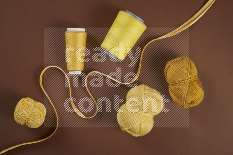 A yellow collection of sewing and tailoring tools arranged on a brown background