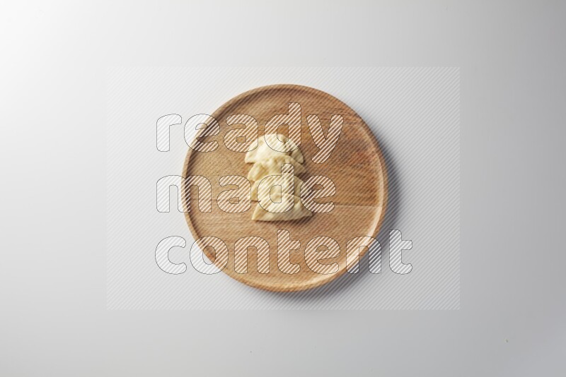 Four Sambosas on a wooden round plate on a white background