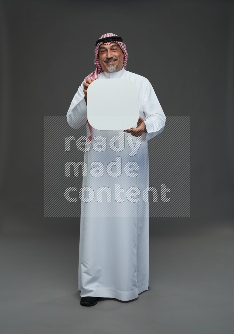Saudi man with shomag Standing holding social media sing on gray background