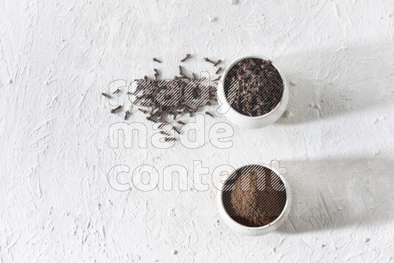 وعاءين من السيراميك بيج اللون، أحدهما مملوء بالقرنفل والآخر مملوء بالبودرة على أرضية بيضاء