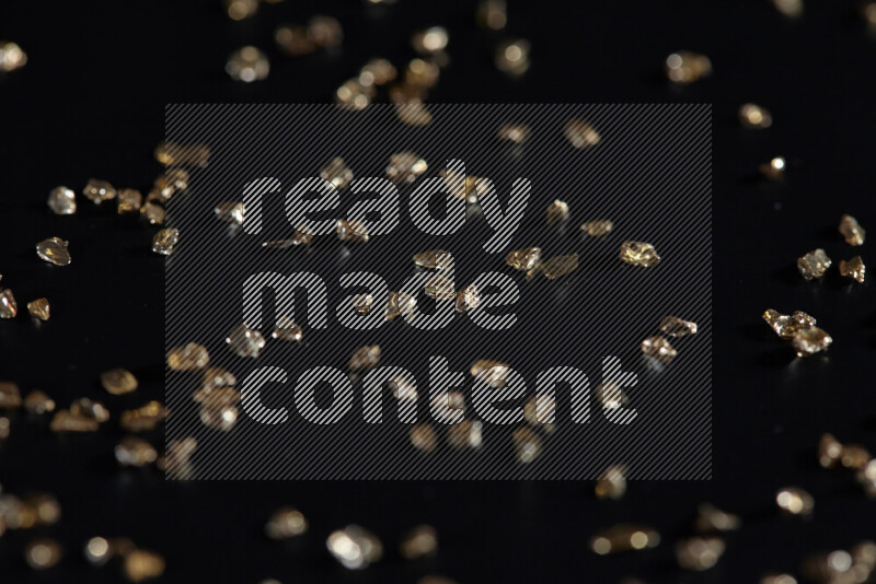 Gold shimmering fragments of glass scattered on a black background