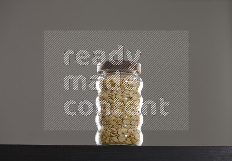 Crushed beans in a glass jar on black background