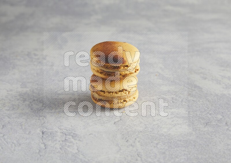45º Shot of two Yellow Crème Brulée macarons on white  marble background