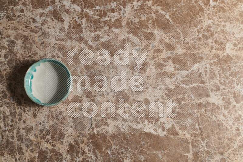 A multicolored pottery bowl on beige marble background