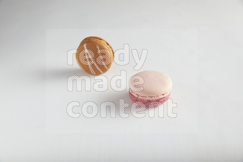 45º Shot of of two assorted Brown Irish Cream, and Pink Litchi Raspberry macarons on white background