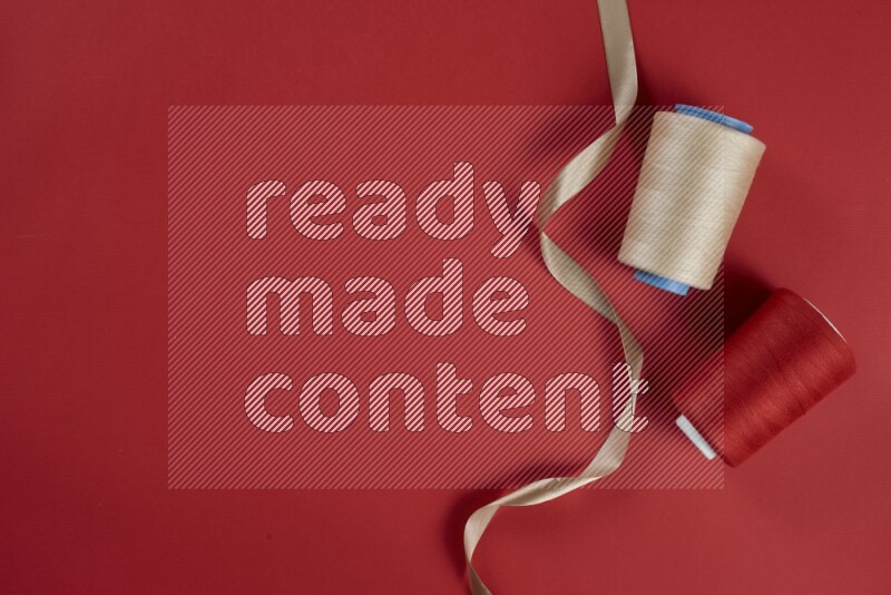 A brown and red collection of sewing and tailoring tools arranged on a red background