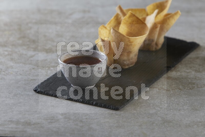 wonton cups with soy sauce ramkin on rectangle slate on grey textured counter top