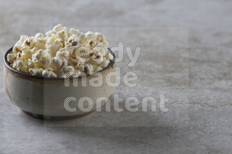 popcorn in multi-colored pottery bowl on a grey textured countertop