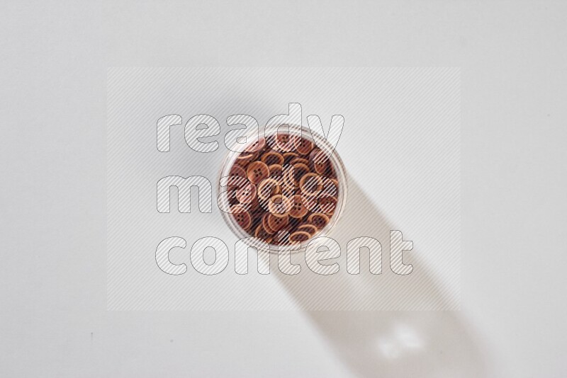 Colored buttons in a glass jar on grey background