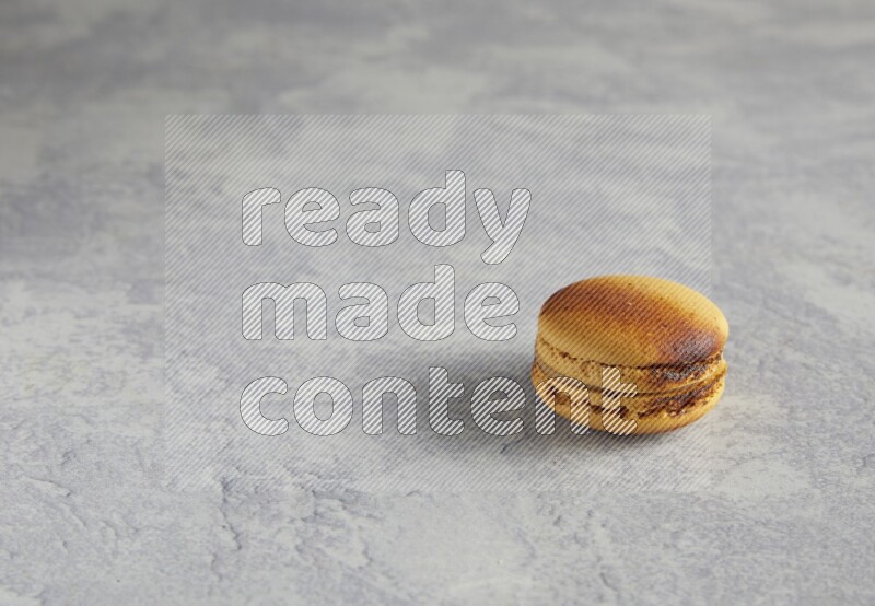 45º Shot of Yellow Crème Brulée macaron on white marble