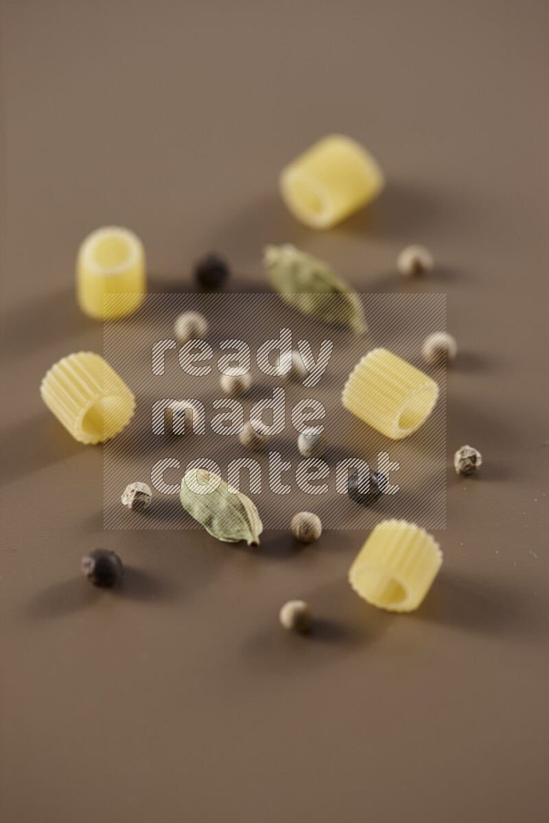 معكرونة مع مكونات متنوعة من الطماطم والثوم والبصل والفلفل الأحمر والفلفل الأسود والفلفل الأبيض وأوراق الغار وإكليل الجبل والهيل على خلفية بيج