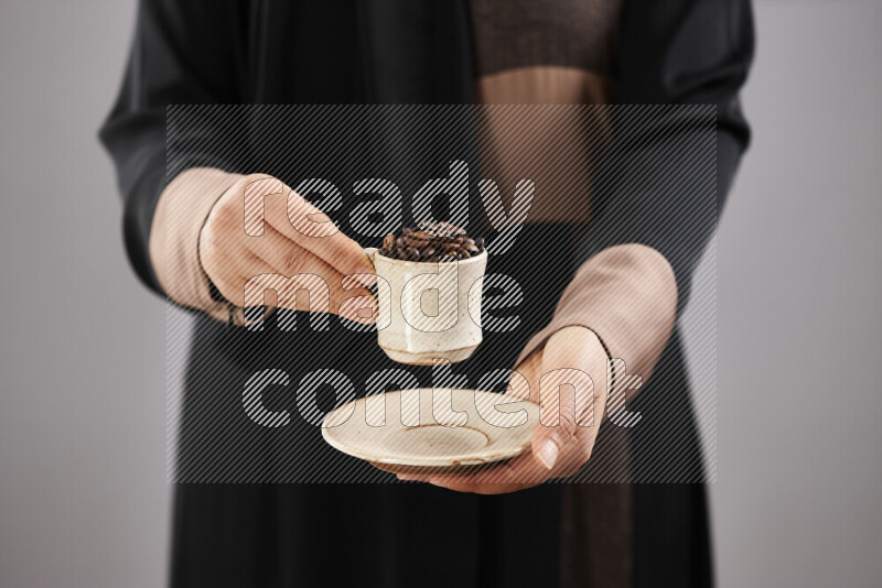 Woman in abaya holding different kinds of coffee beans in different positions