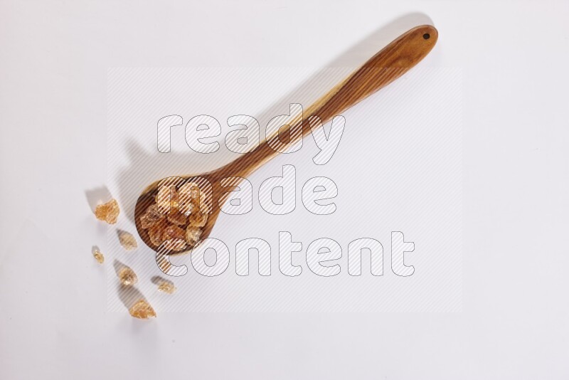 A wooden ladle filled with gum arabic on white flooring