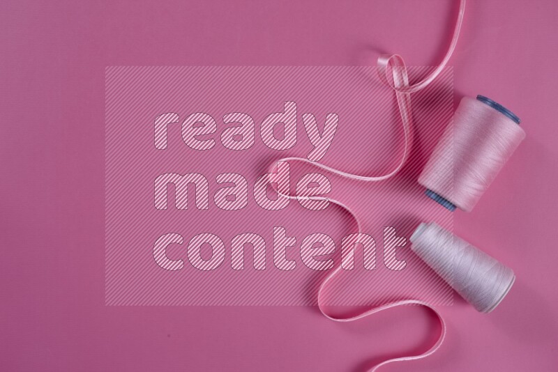 A pink collection of sewing and tailoring tools arranged on a pink background
