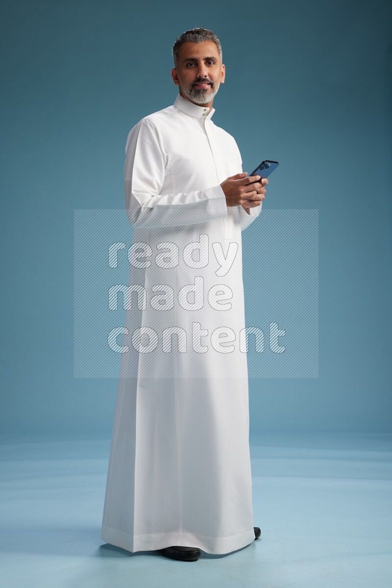 Saudi man waring thob texting on blue background