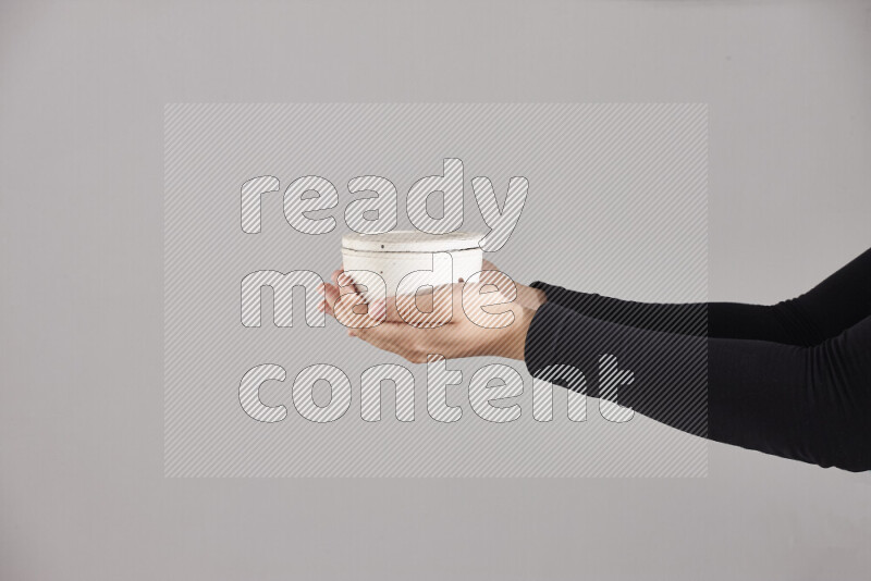 A woman in black abaya holding different pottery essentials in different positions