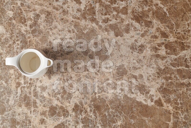 A ceramic milk jug on beige marble background