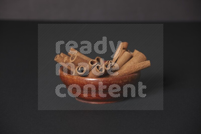 Cinnamon Sticks in a wooden bowl on black background